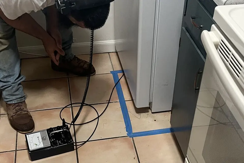 Jeff's Plumbing technician using electronic leak detection equipment on a kitchen floor